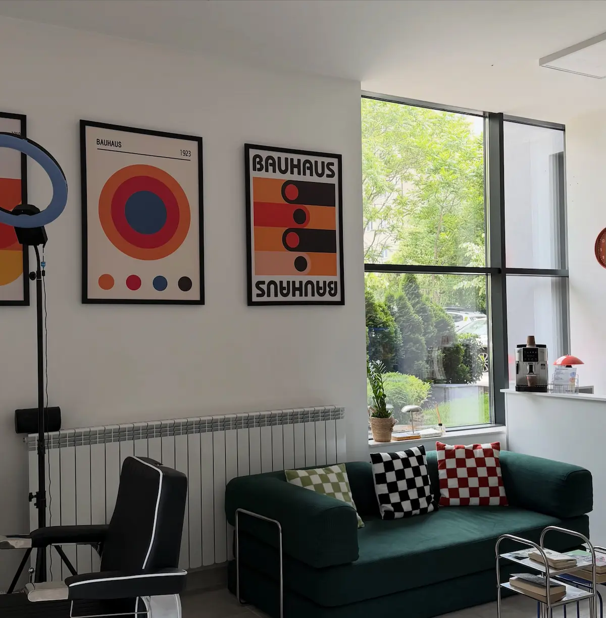 Inside ELEMENT Barbershop — a green velvet sofa and framed Bauhaus prints by the window
