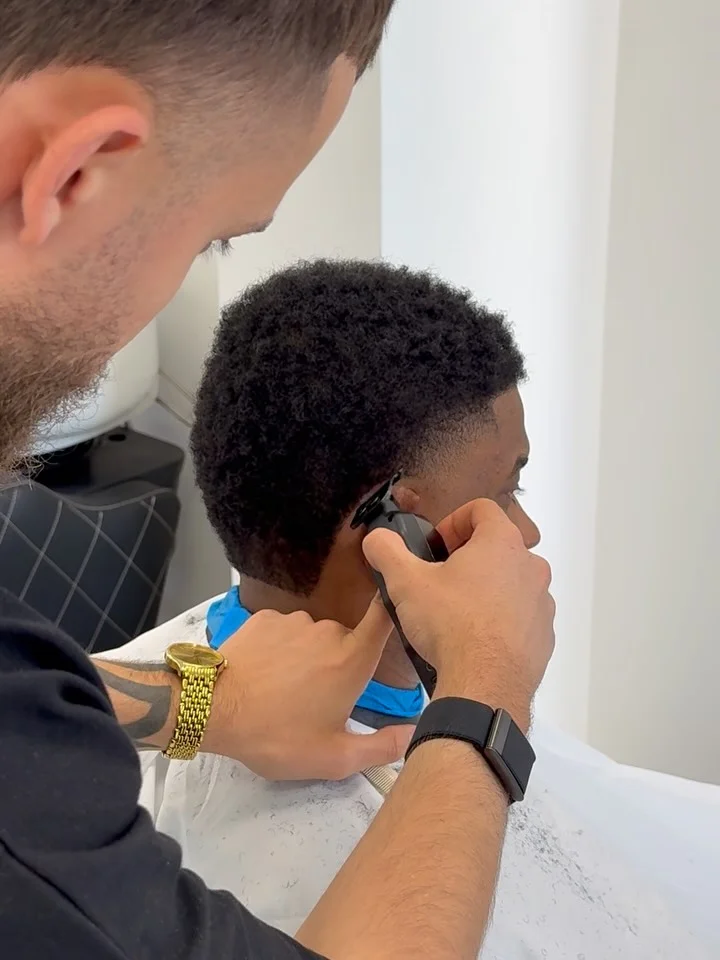 Barber edging a client's hairline with a trimmer