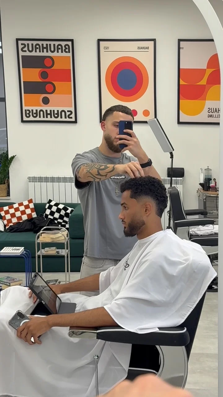 ELEMENT Barbershop interior — a haircut in progress beneath framed Bauhaus prints